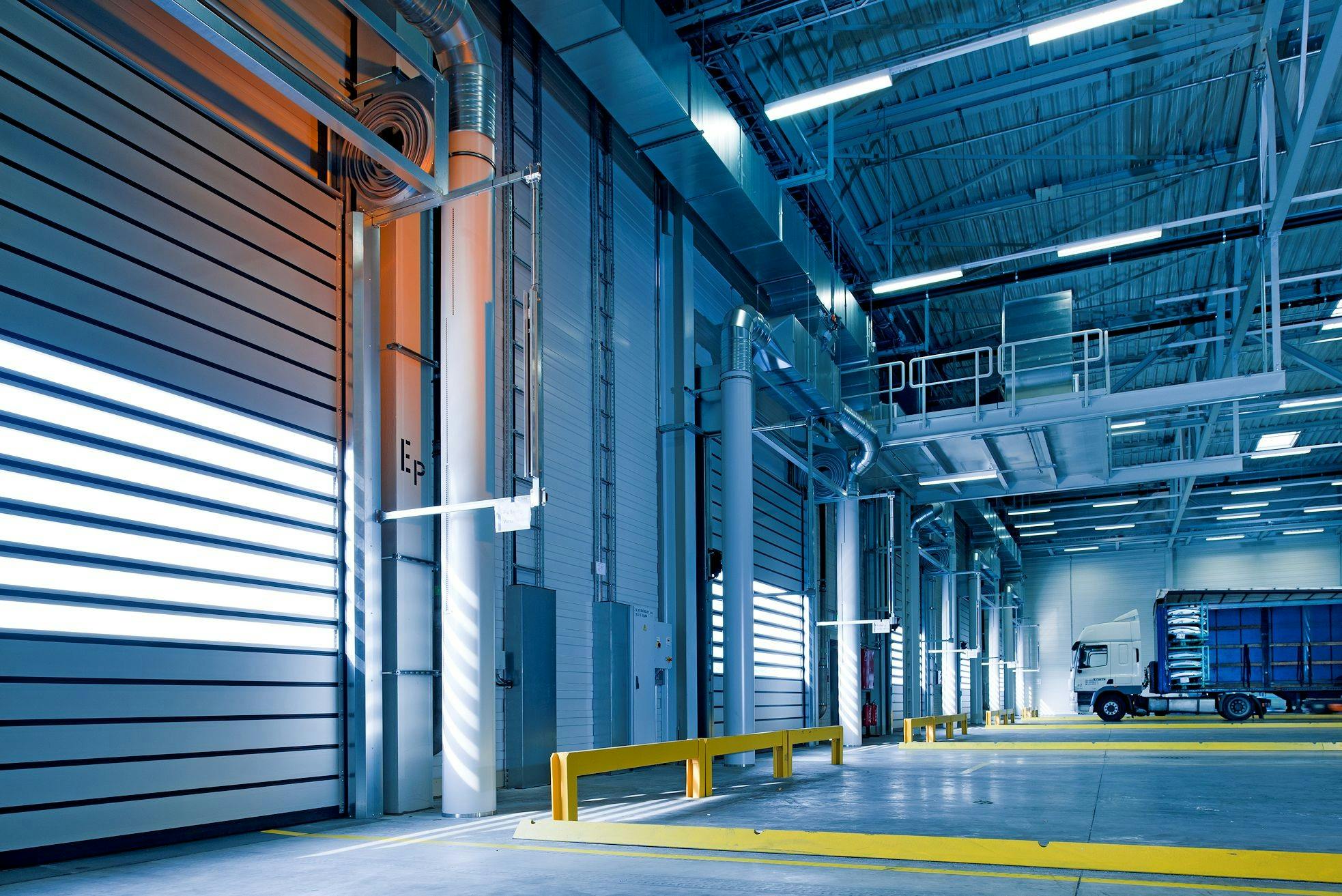 Spacious and modern warehouse interior with parked truck and steel structures.